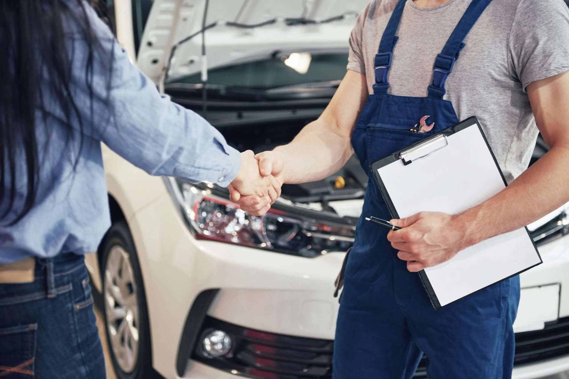 Meccanico che accoglie un cliente davanti all'auto
